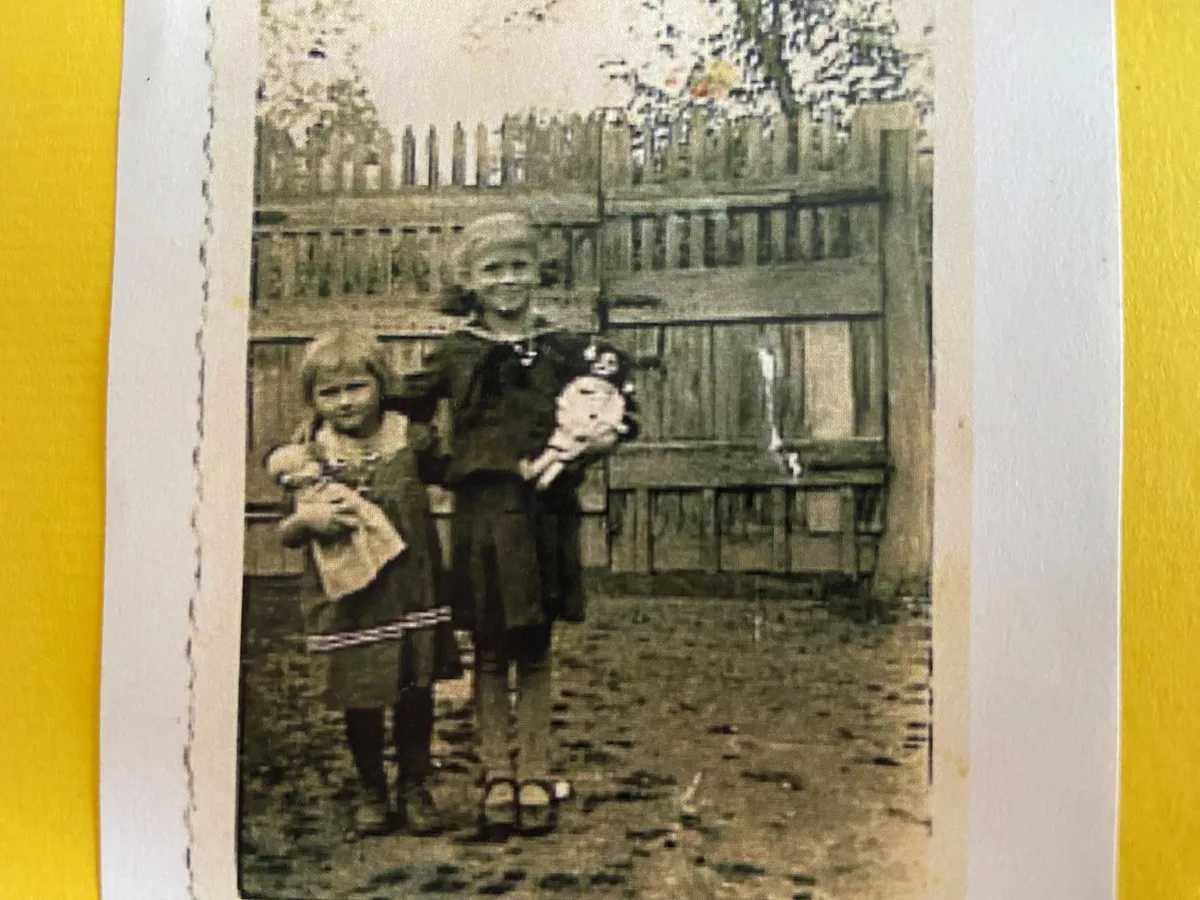 Margrit Gräserund ihre ältere Schwester Theres.  Altes Foto, dahinter ein Gartenzaun.